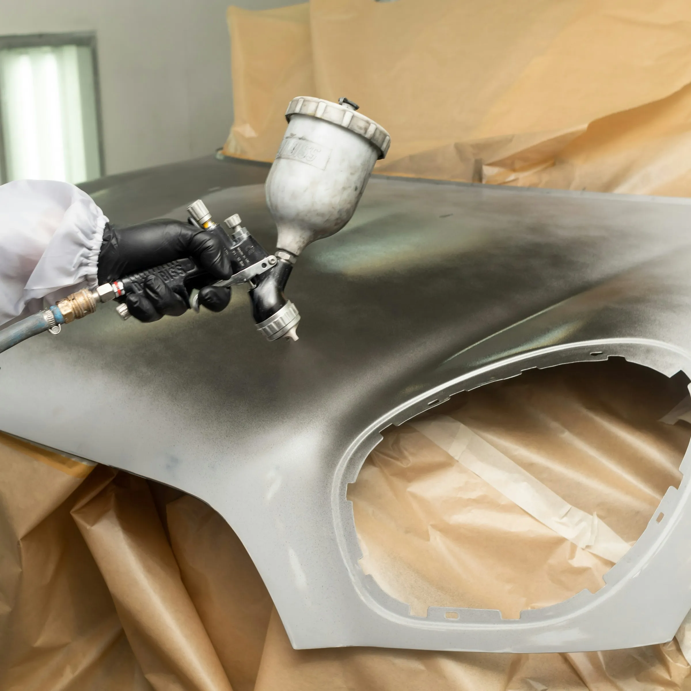 Pistolet de peinture au-dessus d’une pièce apprêtée.